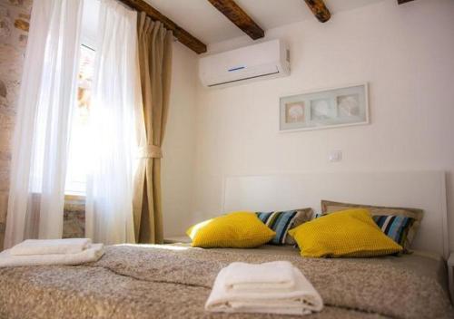 a bedroom with a bed with yellow pillows and a window at Two Friends Dubrovnik Palace in Dubrovnik
