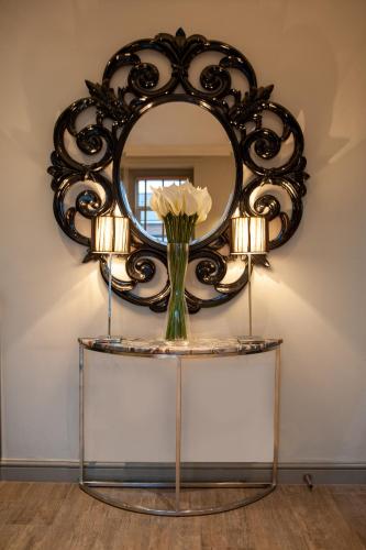 a mirror on top of a table with a vase of flowers at Osborne Hotel in Newcastle upon Tyne
