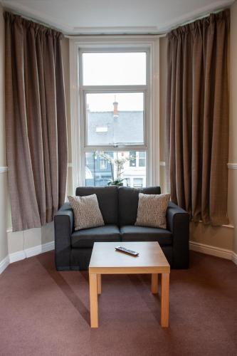 a living room with a couch and a table in front of a window at Osborne Hotel in Newcastle upon Tyne