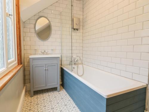Un baño con bañera, lavabo y espejo. en 4 Tan Y Bryn Road, en Llandudno