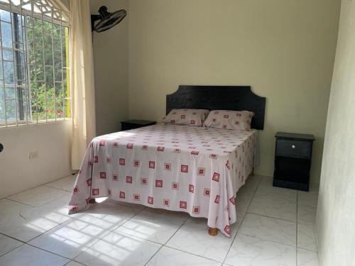 Schlafzimmer mit einem Bett mit einer rosa und weißen Bettdecke in der Unterkunft Tha Lagoon Spots CooL VyBz in Port Antonio