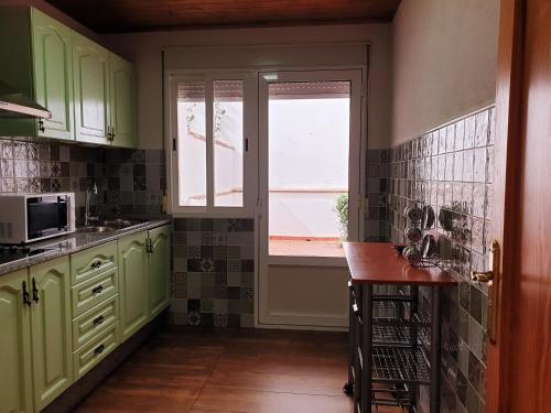 una cocina con armarios verdes y una ventana en Apartamentos El Parral, en Arroyo Frío