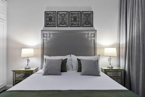 a bedroom with a large white bed with two lamps at Mansions on Pulteney in Adelaide