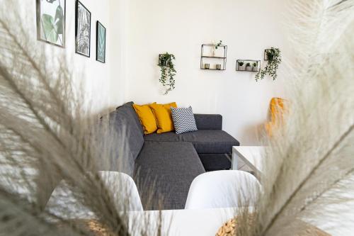 a living room with a gray couch and yellow pillows at Yellow Fresh Apartment 2 in Alexandroupoli