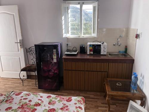 a kitchen with a counter with a sink and a refrigerator at White house in Nainital in Bhīm Tāl