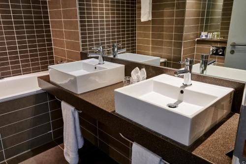 a bathroom with two sinks and a large mirror at Crowne Plaza Manchester City Centre, an IHG Hotel in Manchester