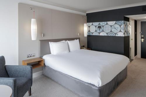 a bedroom with a large white bed and a chair at Crowne Plaza Plymouth by IHG in Plymouth