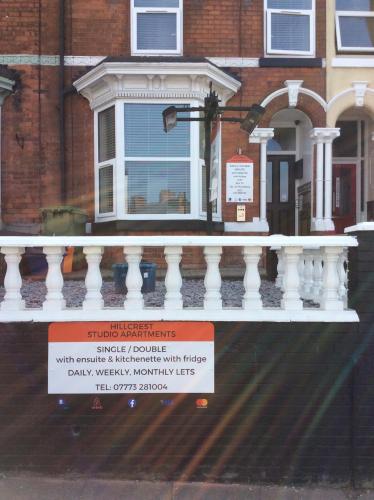 a house with a white balcony with a sign on it at Hillcrest Studio Apartments in Cleethorpes