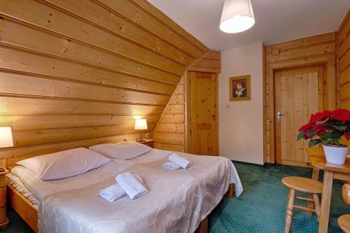 a bedroom with a bed with two towels on it at Góralski Gościniec & SPA in Poronin