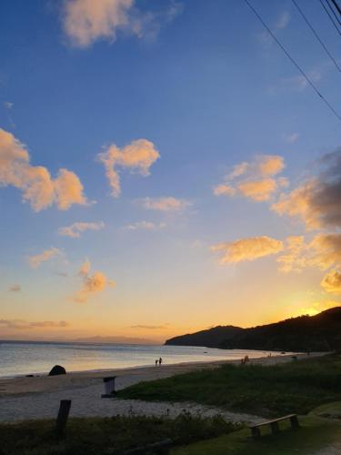 a sunset on a beach with people on the beach at Pousada dos Ingleses in Bombinhas