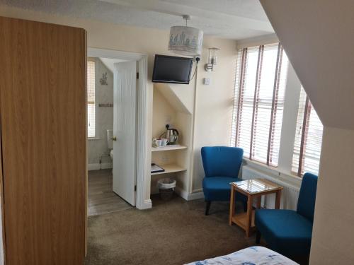 a room with two blue chairs and a television at The Trelinda Guest House in Newquay