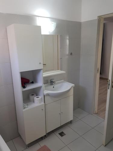 a white bathroom with a sink and a mirror at Apartament 11 Central in Târgu-Mureş