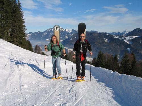 two men standing on a snow covered slope with a snowboard at Ferienwohnung Hell Claudia in Schleching