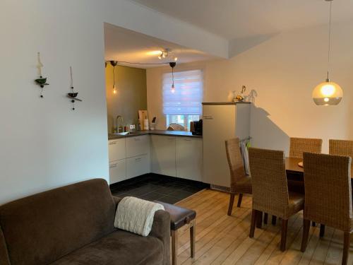 een woonkamer en een keuken met een bank en een tafel bij Huize Bronsgroen - vakantiehuis voor 2-6 pers in Limburgse Heuvelland in Cadier en Keer