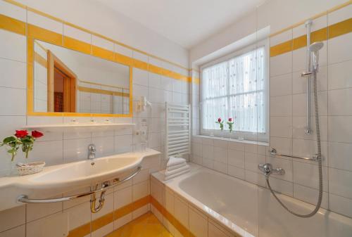 a bathroom with a tub and a sink and a shower at Hotel Fischerwirt Natur WaldSPA in Faistenau