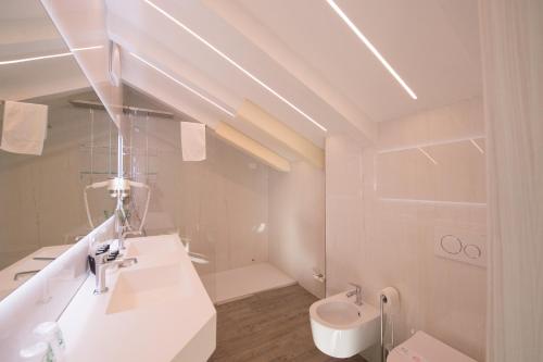 a white bathroom with a sink and a toilet at Grand Hotel Liberty in Riva del Garda