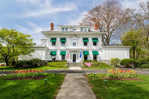 a white house with green shutters and flowers at Stanton House Inn in Greenwich