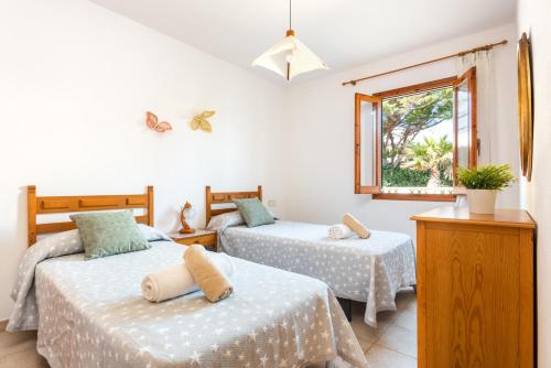 a bedroom with two beds and a window at Casa Marinada in Es Mercadal
