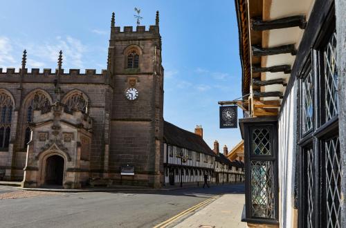 an old building with a clock tower on a street at Hotel Indigo - Stratford Upon Avon by IHG in Stratford-upon-Avon