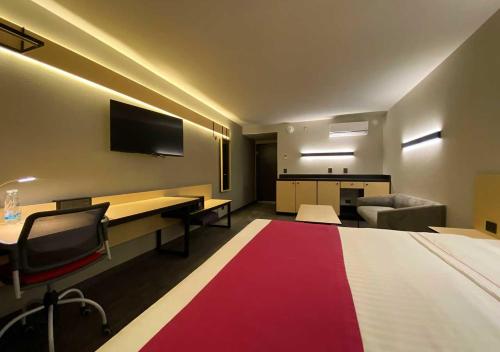 a room with a bed and a desk and a tv at Hotel MX mas cuautitlan Izcalli, Trademark by Wyndham in Cárdenas