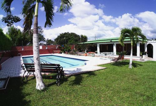 a swimming pool with a bench next to a palm tree at Caraná in Pueblo Tapao