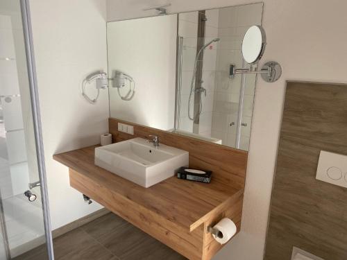 a bathroom with a white sink and a shower at Apartmenthaus Krone Wohnen mit Herz in Bexbach