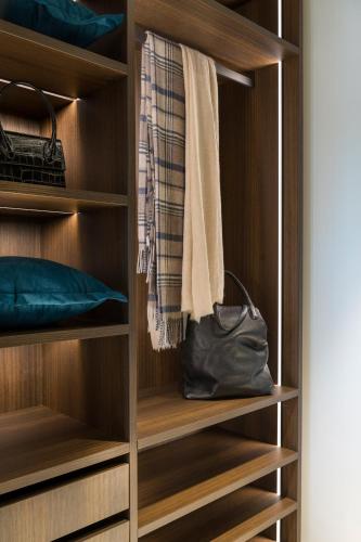 a walk in closet with wooden shelves and a purse at We Me Suite Hotel in Riccione