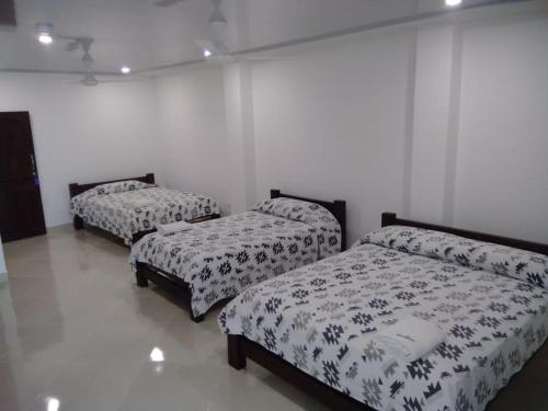 three beds in a room with white walls at HOTEL TANIA in Caucasia