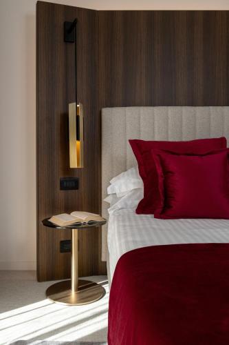 a bedroom with a bed with red pillows and a table at We Me Suite Hotel in Riccione