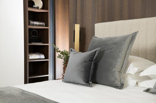 a bed with two pillows and a book shelf at We Me Suite Hotel in Riccione