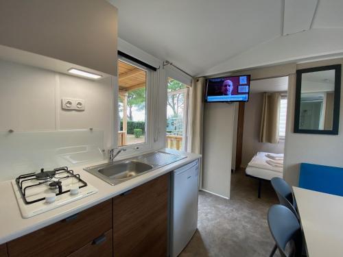 uma cozinha com um lavatório e uma televisão numa caravana em Camping Serenella em Bardolino