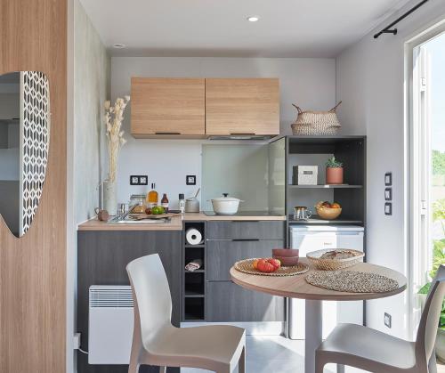 a kitchen with a table and chairs in a room at Camping Du Paquier Fané in Chagny