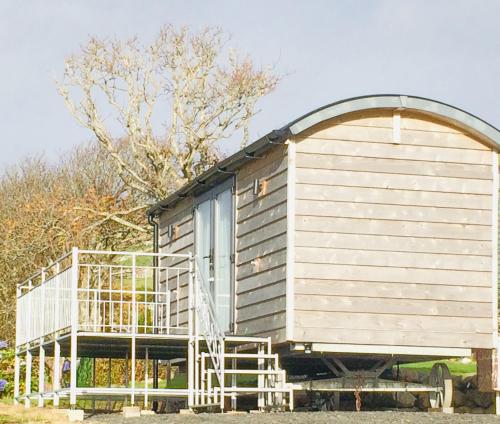 a wooden cabin with a large door and a balcony at Cwt y Bugail in Barmouth