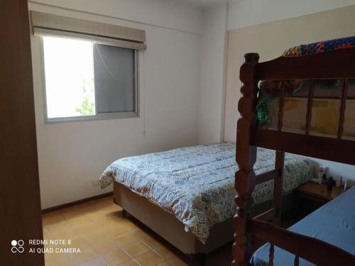 een slaapkamer met een bed en een raam bij Aconchegante e Amplo Apartamento Familiar pertinho da Praia! in Guarujá