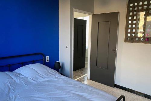 Dormitorio azul con cama y espejo en Appartement indépendant dans maison de village, en Saint-André-de-Sangonis