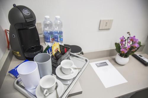 uma mesa com chávenas, comodidades para preparar café e flores em Correnti Boutique Hotel em Sanremo