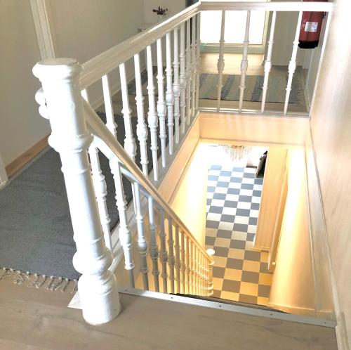 a hallway with a staircase with a checkerboard floor at Sandkaas Badehotel in Allinge