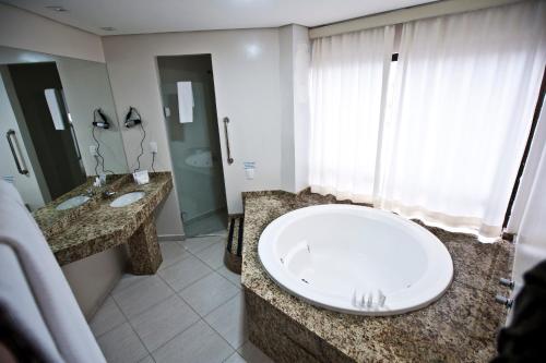 a bathroom with two sinks and a large tub at Hotel Lang Palace - Fica no Centro da Cidade in Chapecó