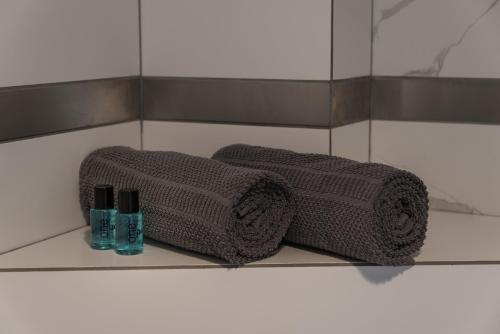 due asciugamani e due bottiglie su una mensola in bagno di Magnetic apartment Jerozolimskie A a Varsavia