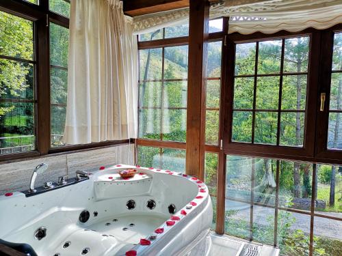 a bathroom with a large tub in a room with windows at Akla La Casa Del Puente in Regules