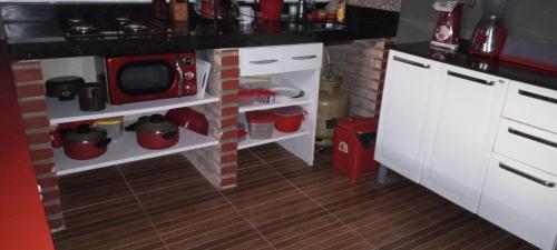 a kitchen with white cabinets and a red microwave at Cantinho Nativus in Maragogi