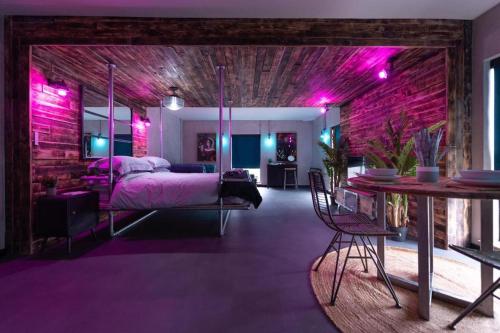31B Urban Stays في نورويتش: غرفة نوم مع إضاءة أرجوانية وسرير وطاولة