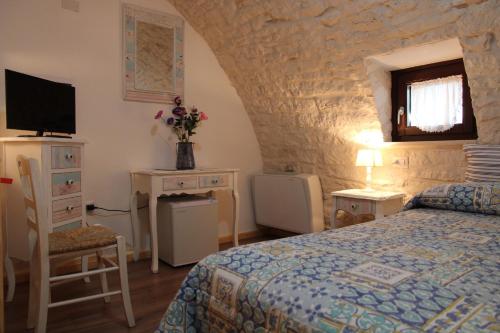 a bedroom with a bed and a tv and a chair at B&B Trulli Donna Isabella in Locorotondo