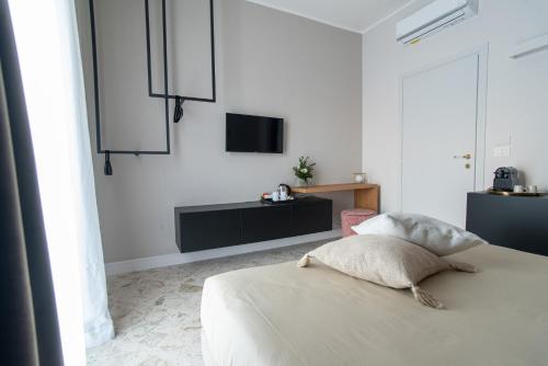 a white bedroom with a bed and a tv on the wall at Casa Almika Sparano in Bari