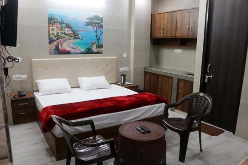 a bedroom with a bed and a chair and a painting at Krishna Dreams in Haridwār
