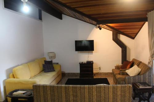 ein Wohnzimmer mit einem Sofa und einem TV in der Unterkunft Casa Fazenda Inglesa Petrópolis RJ in Petrópolis