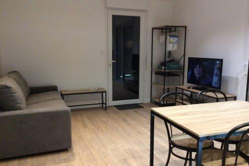 a living room with a couch and a table at Petite maison au calme tout confort in Challans