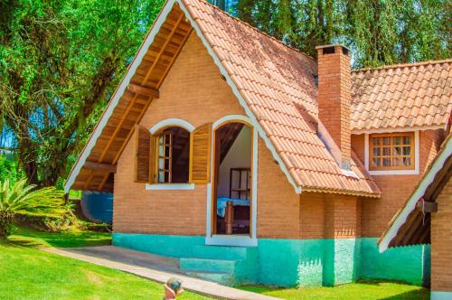 a small brick house with a red roof at Pousada Vale Verde in Monte Verde