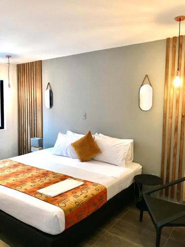 a bedroom with a large bed and a chair at HOTEL CASA MAYOR LA 70 in Medellín