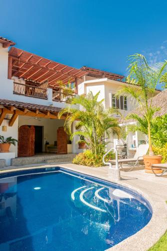a swimming pool in front of a house at Villas Sunrisa in Zihuatanejo